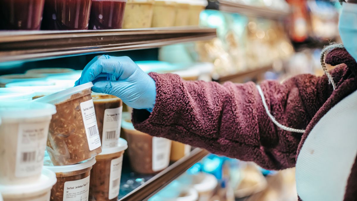 Shopper choosing a packaged product from a supermarket freezer aisle