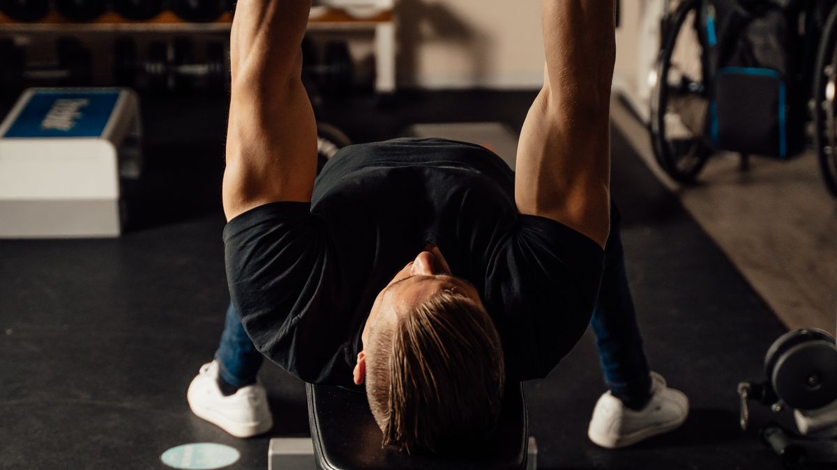 Person lifting weights in a gym while progressively increasing training load