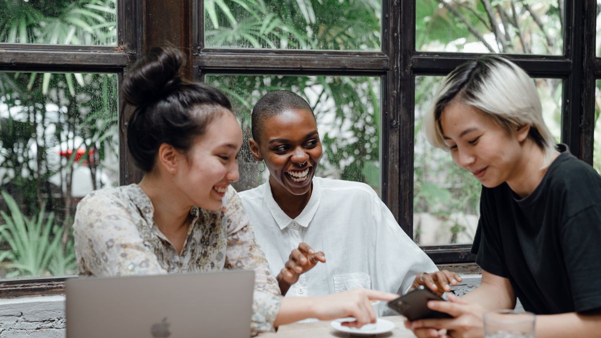Friends laughing together in a cafe as an offline mental health boost