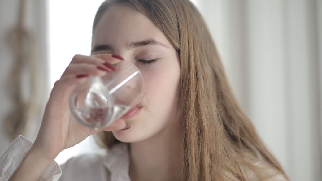 Woman drinking a glass of water to help prevent a urinary tract infection