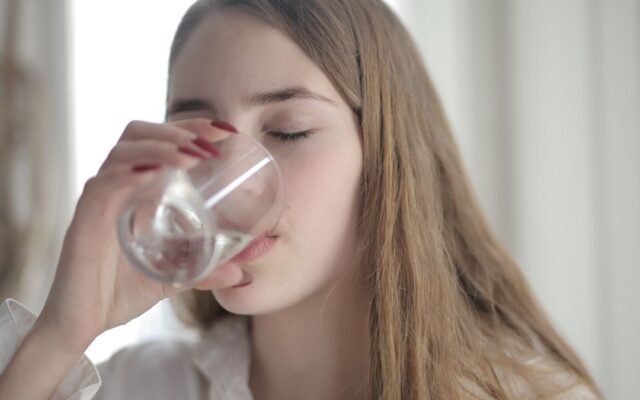 Woman drinking a glass of water to help prevent a urinary tract infection