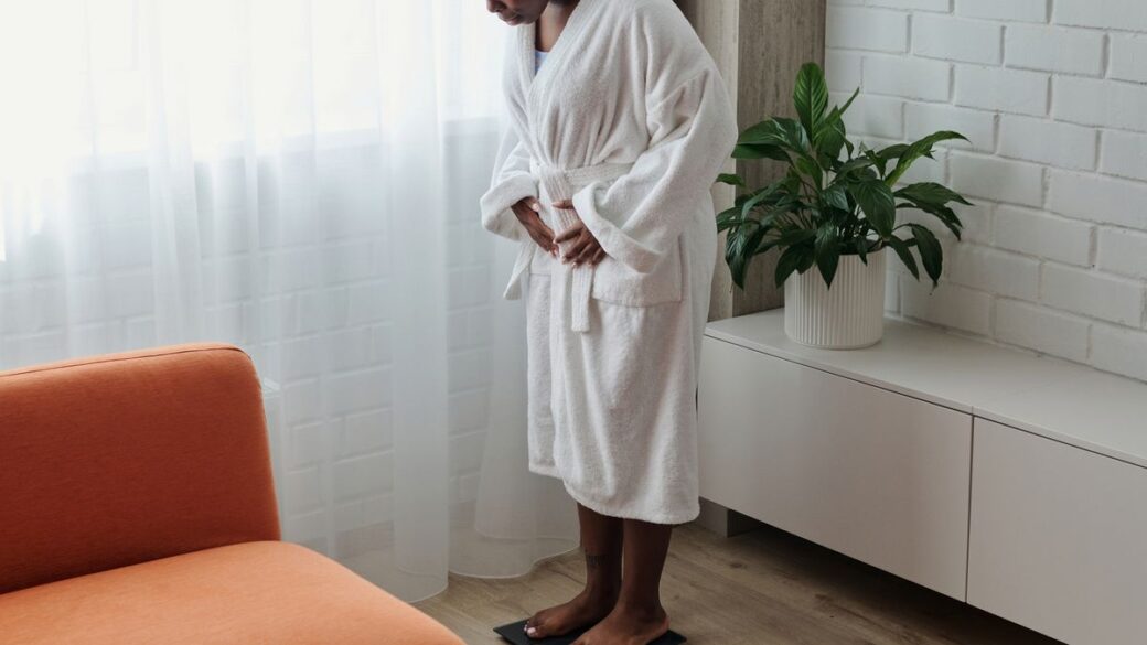 Woman standing on a bathroom scale checking her weight during a yo-yo dieting cycle